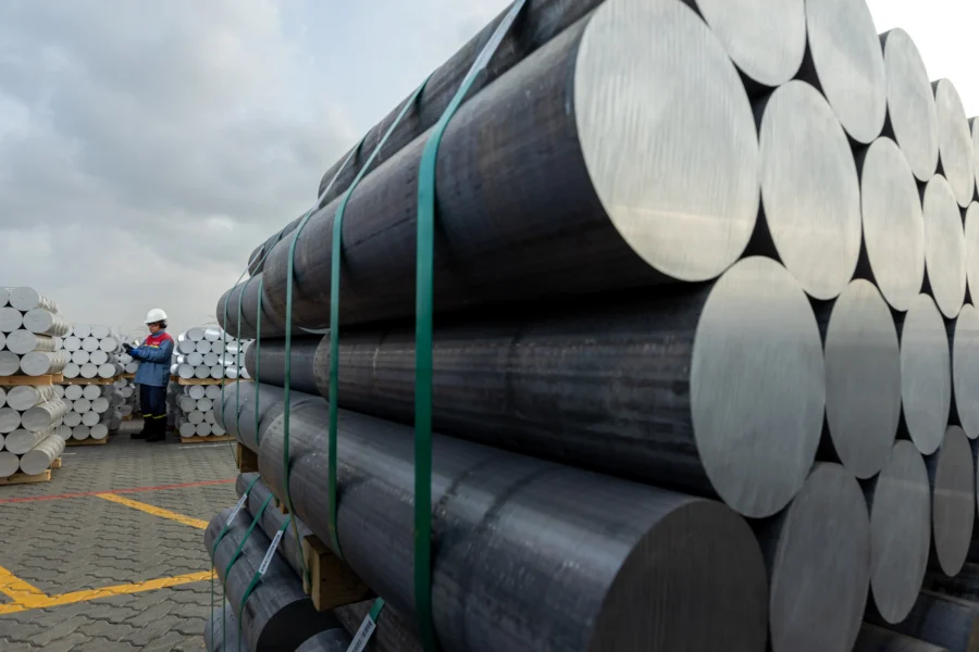 Hundreds of billets are bound together while a worker analyzes and makes notes of the pallets.