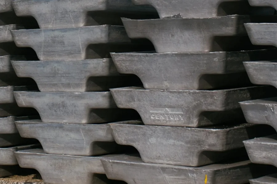 Stacked aluminum ingots with "CENTURY" embossed on one, arranged in rows outdoors.
